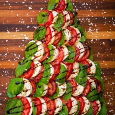 Caprese salad shaped like a Christmas tree, featuring tomatoes and mozzarella.