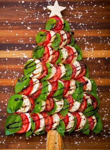 Caprese salad shaped like a Christmas tree, featuring tomatoes and mozzarella.