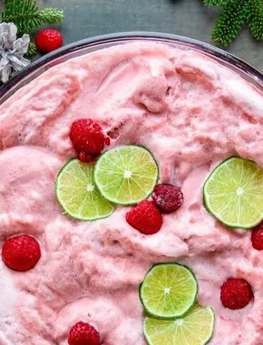 A festive bowl of Sherbet Christmas Punch with colorful fruits and decorations