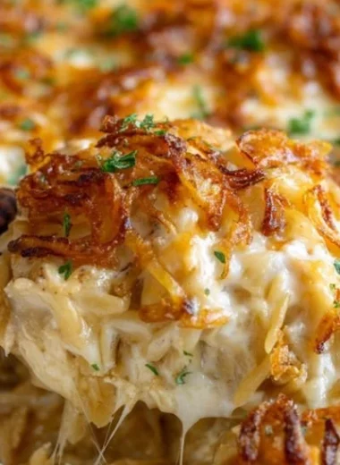French Onion Chicken Orzo Casserole topped with melted cheese and crispy onions.