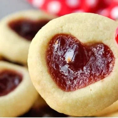 Heart Jam Cookies on a plate decorated with powdered sugar and fresh berries