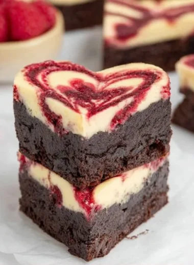 Heart-shaped brownies served on a plate, decorated with frosting and sprinkles